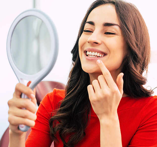 woman looking at her smile in a mirror