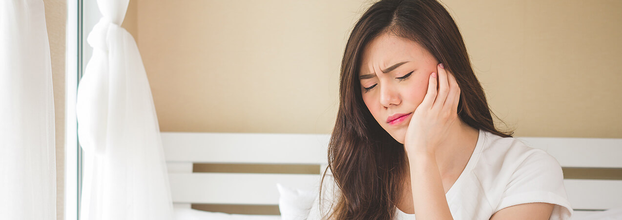 woman holding her jaw in pain