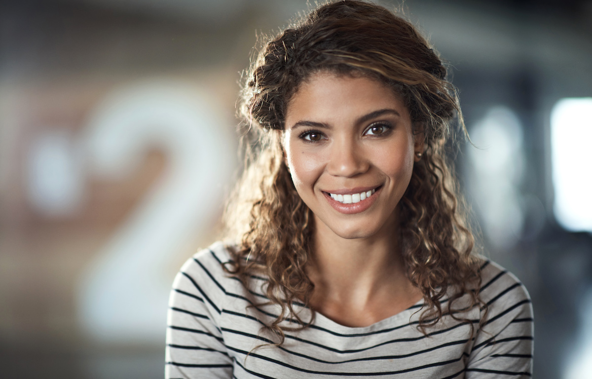 Headshot of a smiling curly-haired woman wearing a striped shirt