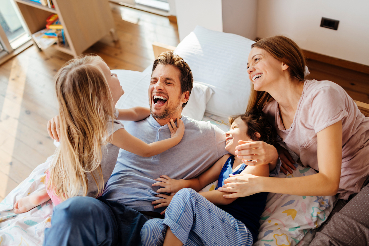 Mom and dad laugh together with their young daughters at edgewood family dentistry, a dentist in Anderson, IN