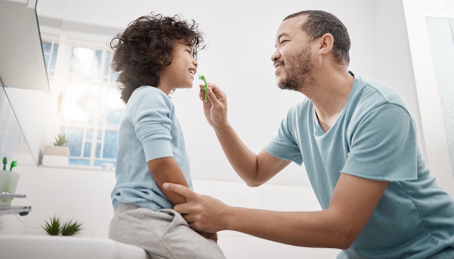 father brushing child's teeth to prevent baby tooth fillings and baby teeth cavities