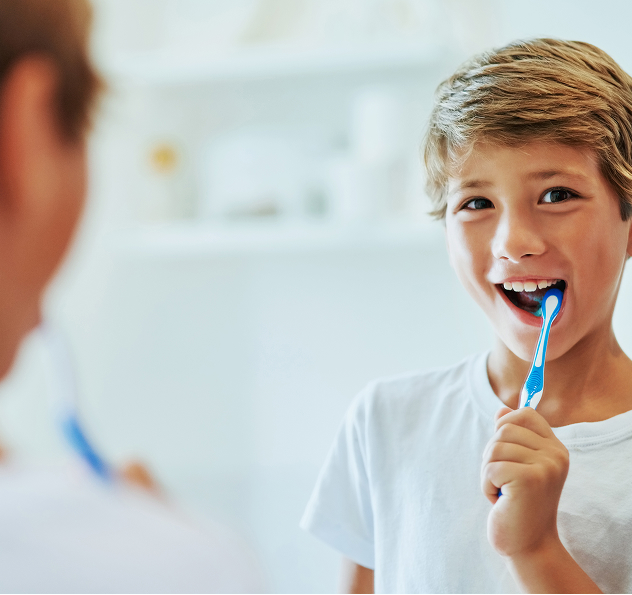 boy brushing his teeth in mirror