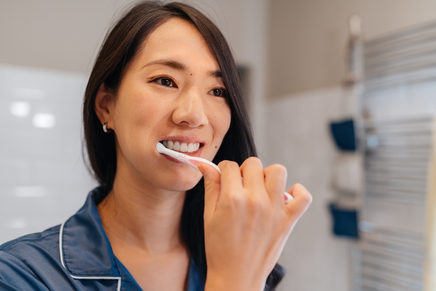 woman brushing her teeth for healthy dental habits