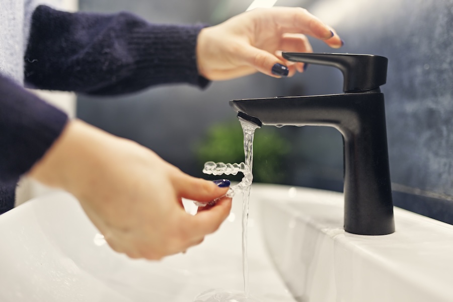 woman rinsing invisalign aligners